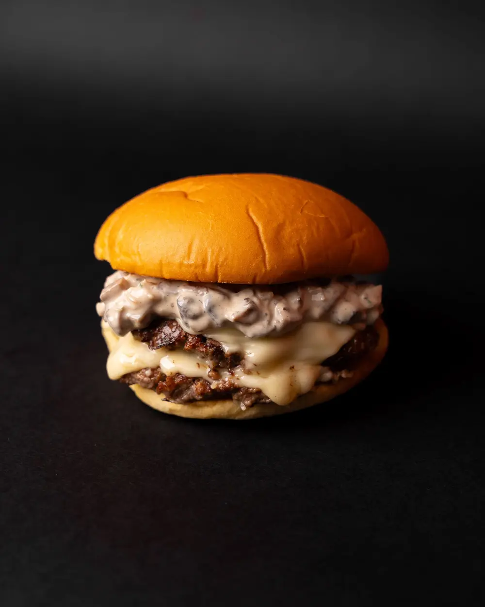 Double cheeseburger with melted cheese on a dark background