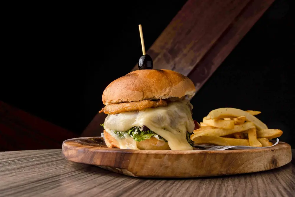Cheeseburger with fries on a wooden board