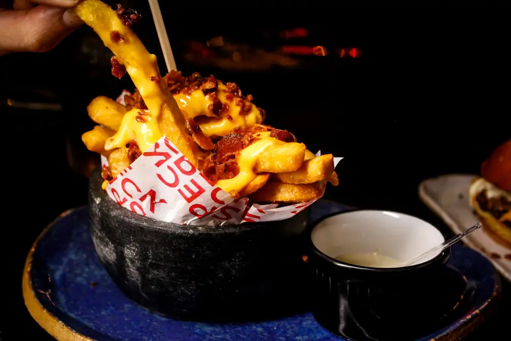 Fries loaded with cheese sauce being lifted with a fork