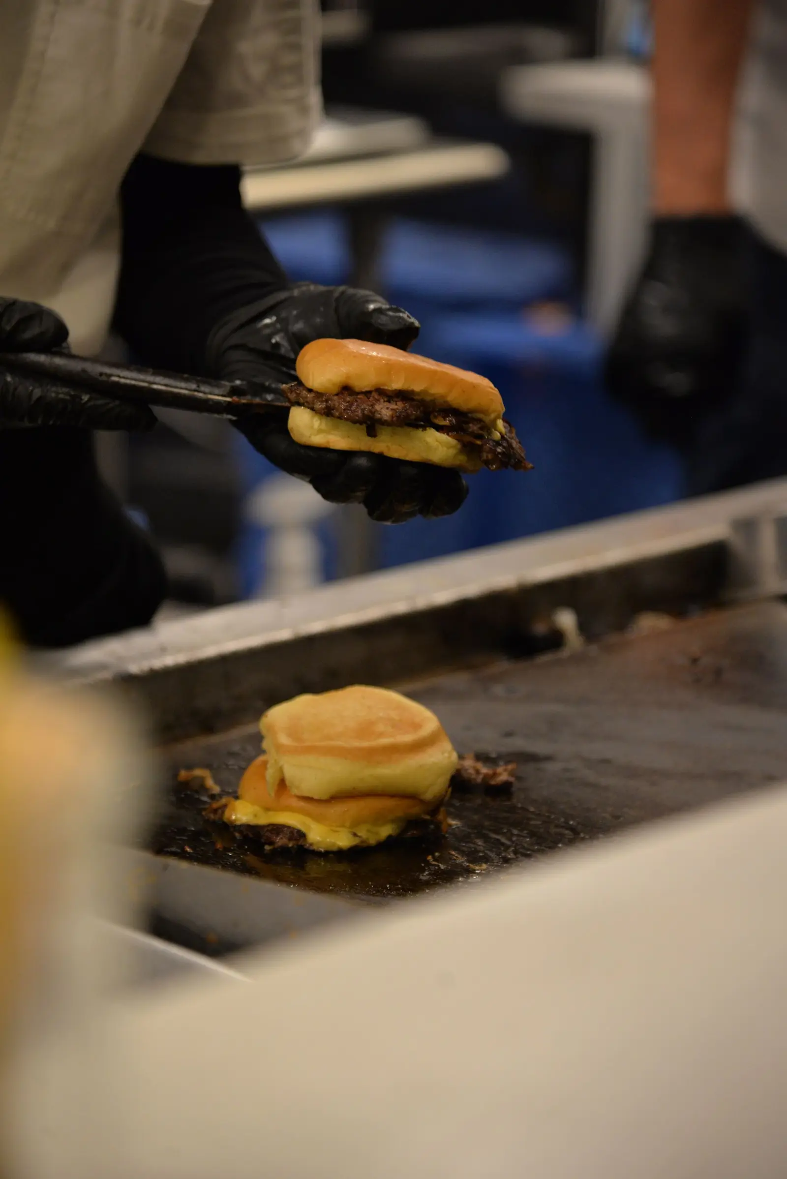 Cook lifting a cheeseburger off the flat-top